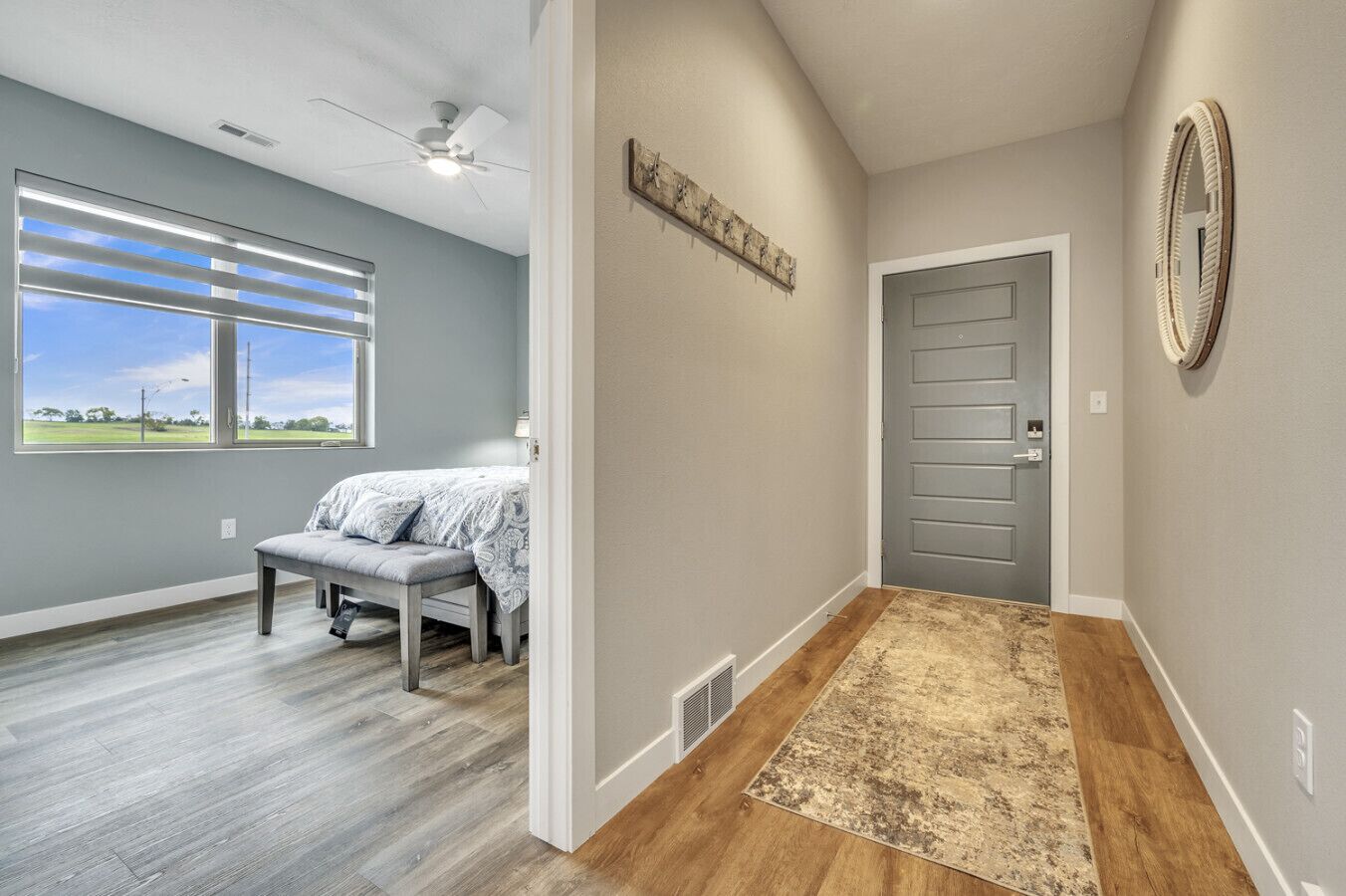 Une chambre à coucher avec un lit, un banc, une fenêtre avec des stores et une porte.