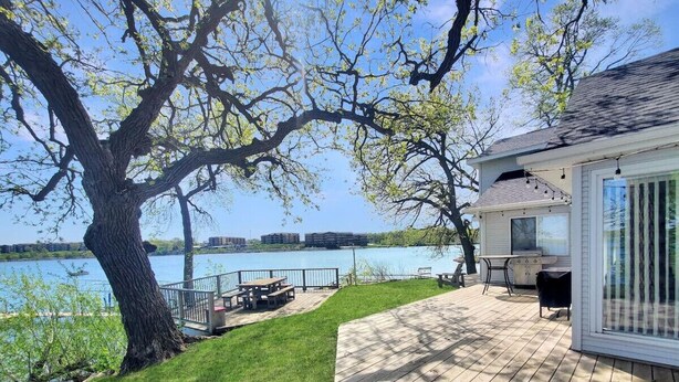 A deck with a grill and outdoor seating, overlooking a lake. - The Lakeside Lookout on East Lake`s Gingles Point (Arnolds Park)