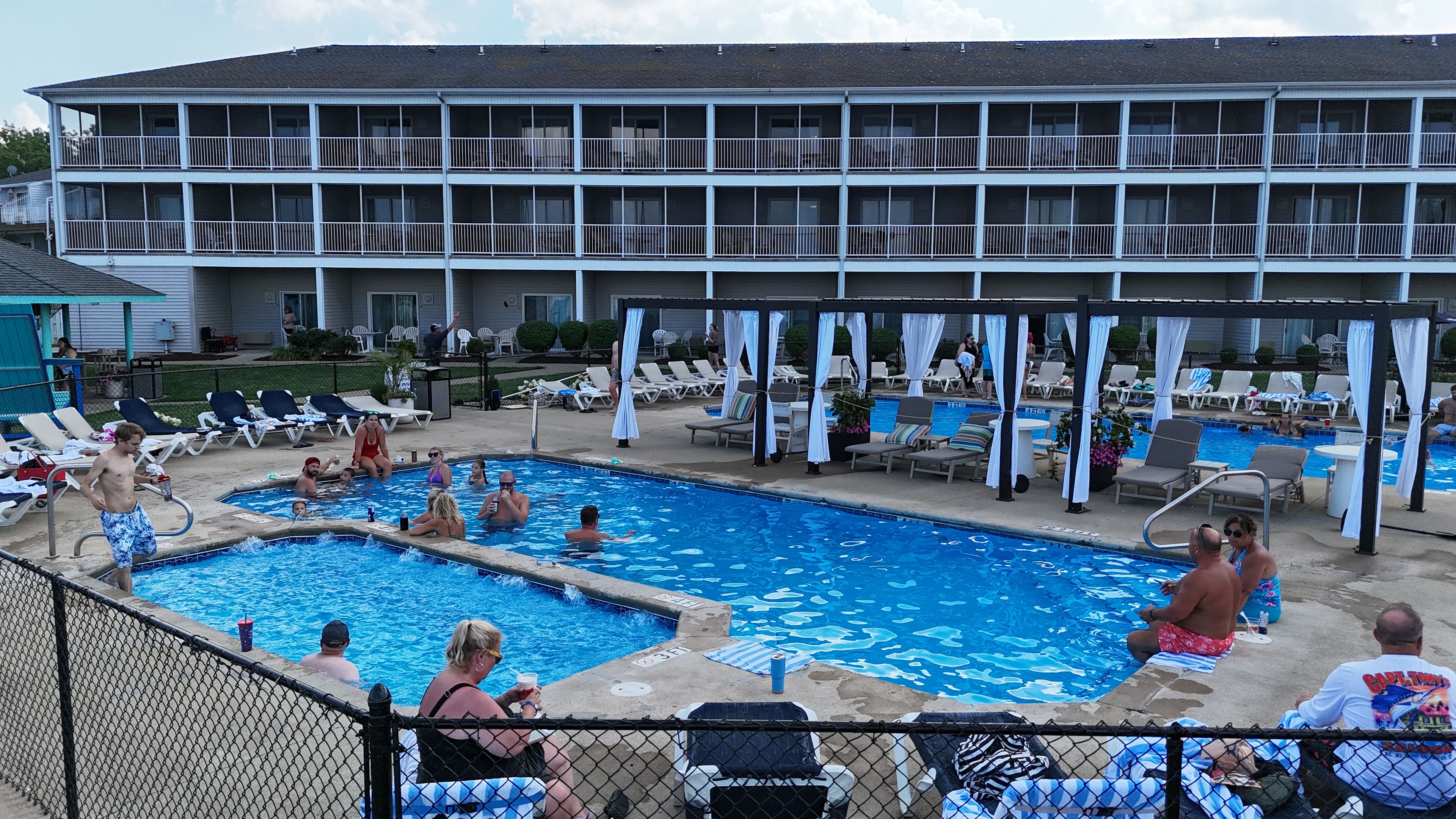 Zona de piscina con sillas de descanso y un área de estar techada.
