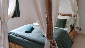 A bed with a green bedspread and pillows, a white canopy, and a wooden headboard. - Ô Licuala Villa (Petite Île)