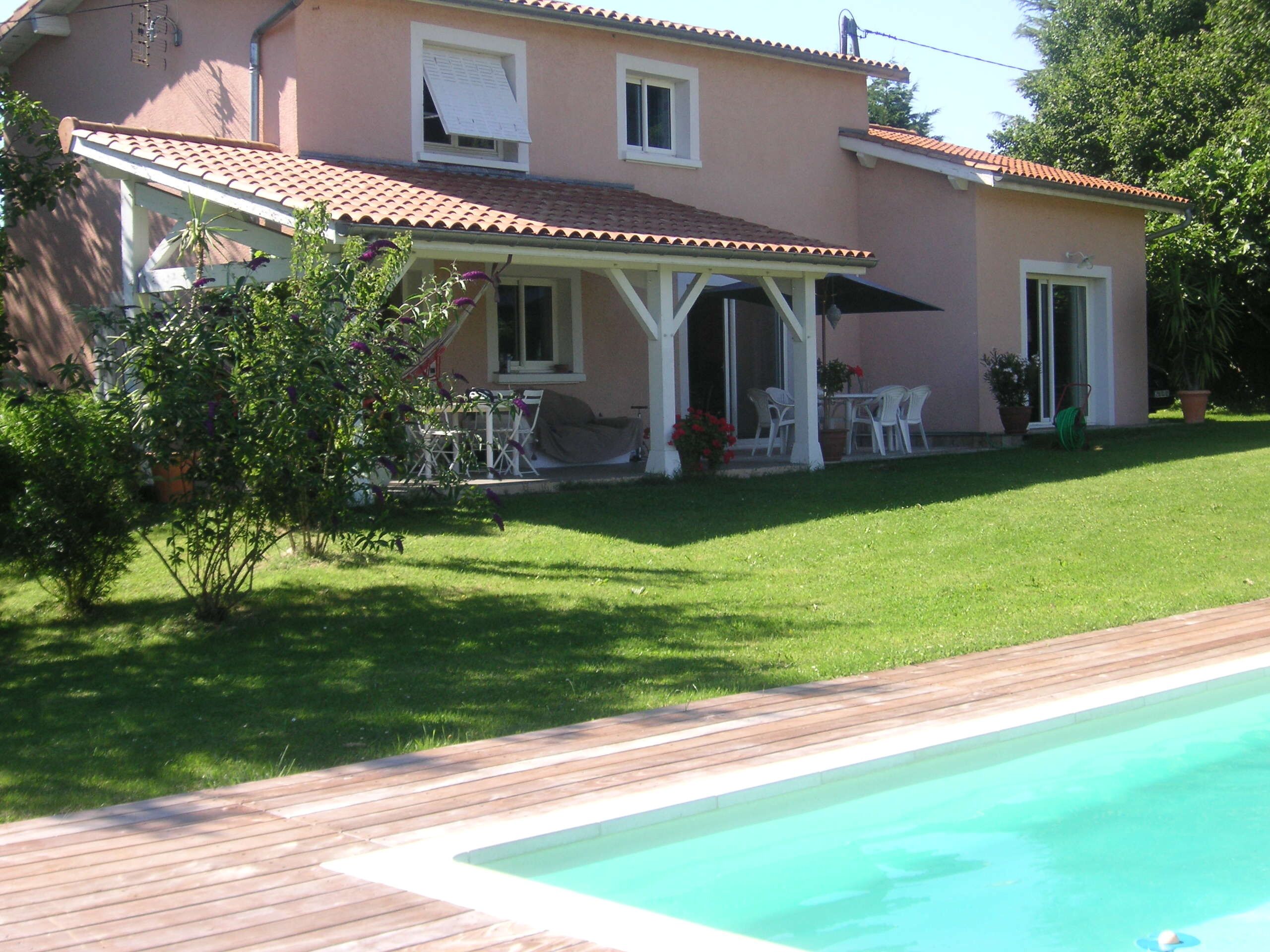 A house with a swimming pool, a patio with outdoor furniture, and a well-maintained lawn.