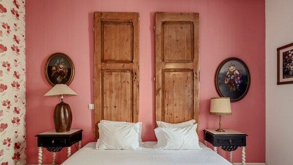 Classic bedroom with a double bed, nightstands, and framed pictures.