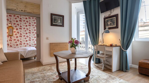 Une pièce confortable avec un lit, un bureau et une petite table agrémentée de fleurs.