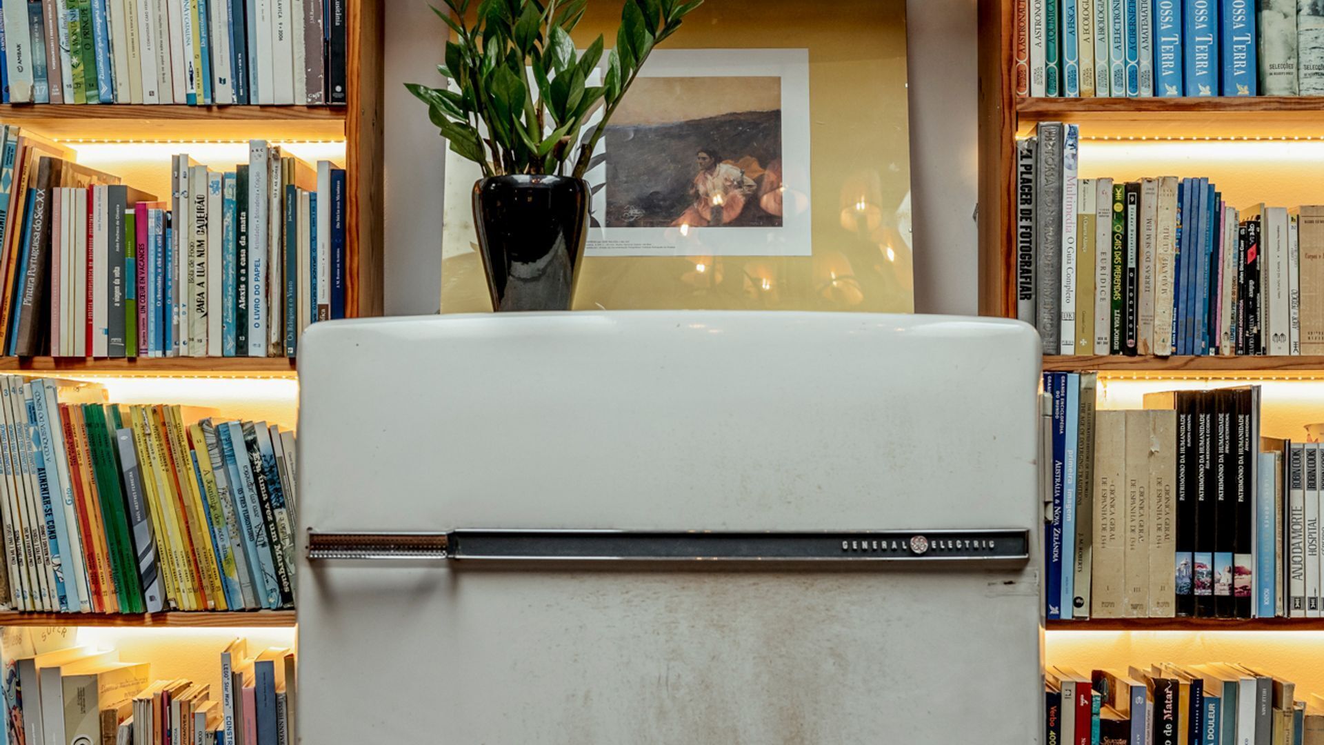 A white refrigerator with a General Electric logo, surrounded by bookshelves filled with books.