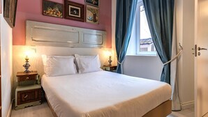 Ein ordentlich bezogenes Bett mit weißen Leinen, zwei Nachttische mit Lampen, ein Kopfteil und ein Fenster mit Vorhängen.