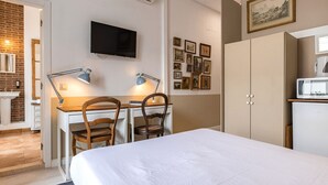 Un dormitorio con cama, escritorio con dos sillas, televisor montado en la pared y armario.
