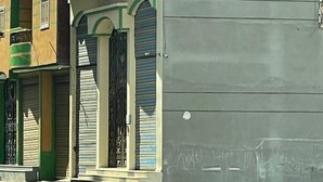 A multi-story building with a green and beige facade, featuring balconies and a large garage door. - بيت عطلات (Awlad Saqr)
