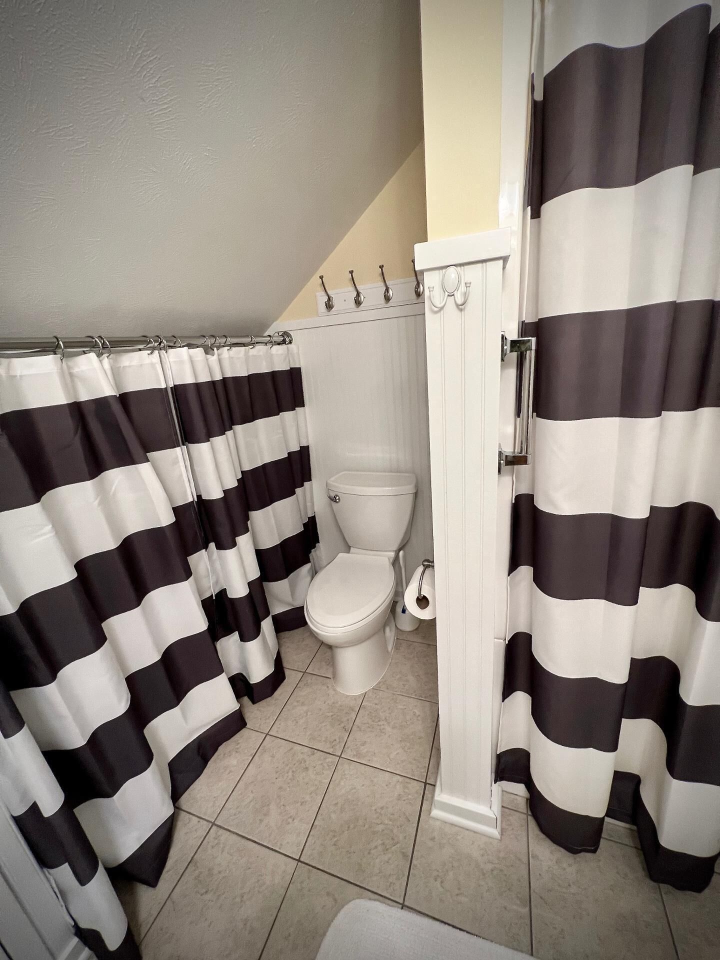 Ein Badezimmer mit Toilette, Duschvorhang und Handtuchhalter.