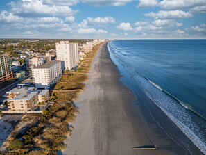 A coastal cityscape with a long sandy beach, high-rise buildings, and a clear blue sky. - Private Family Friendly home just a few blocks from Beach:Hot Tub, Grill, Golf (North Myrtle Beach)