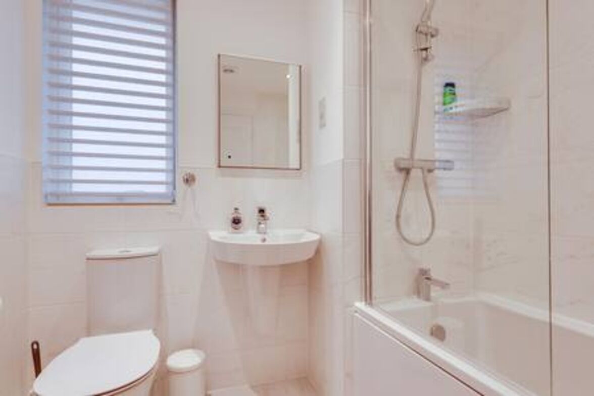 A modern bathroom with a toilet, sink, and glass-enclosed shower.