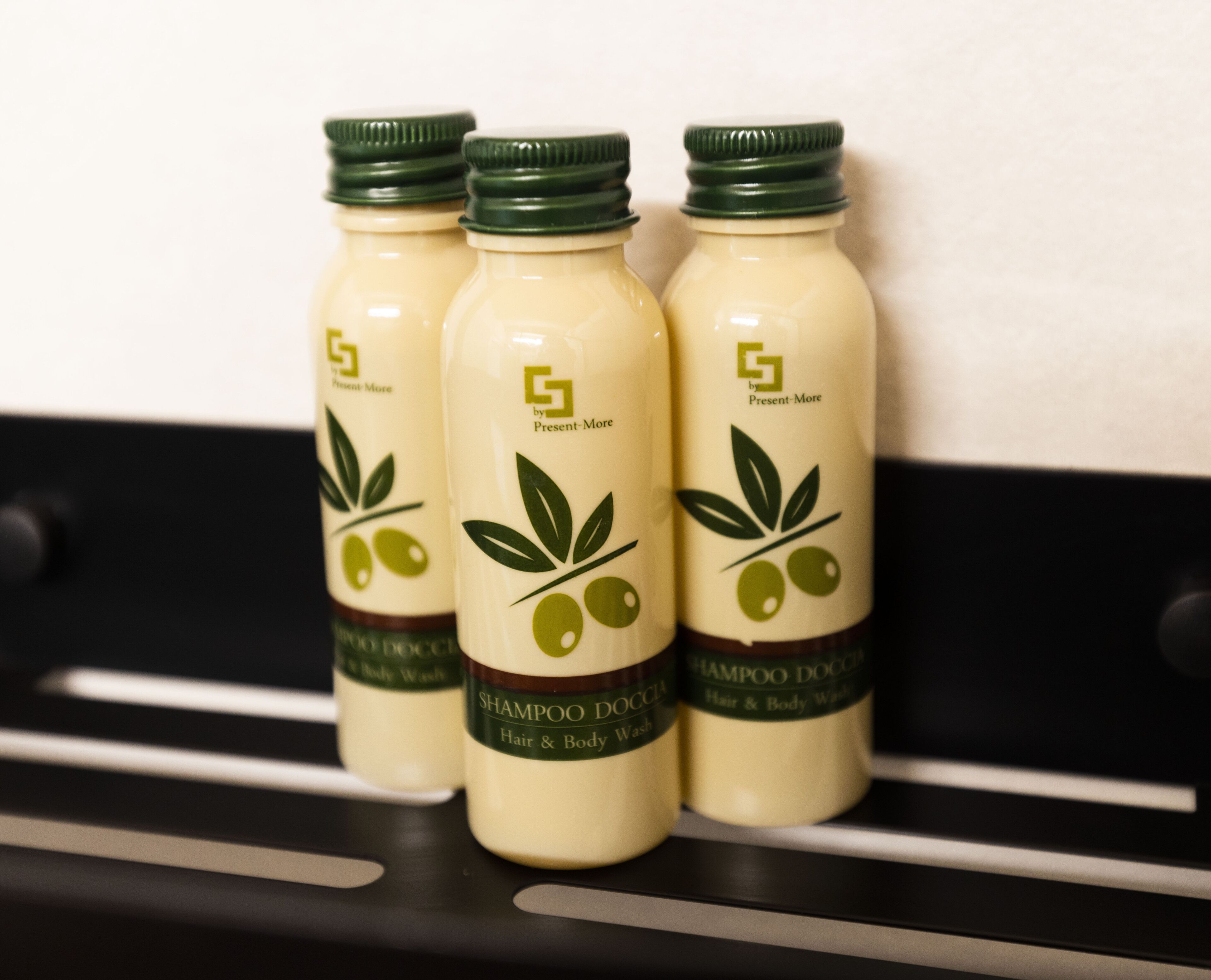 Drie flessen shampoo op een plank.