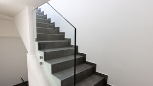 A modern staircase with a glass railing and grey steps.