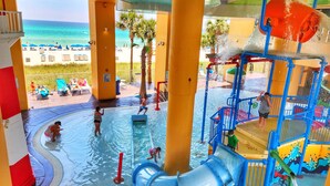A water park with a pool, slides, and a beach view. - Splash Resort 1403E 🏖 Beachfront Luxury & Free Chairs ✨️ Mega Vacations PCB (Panama City Beach)