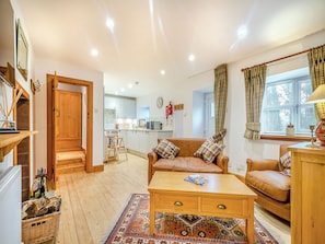 A cozy living room with a brown leather sofa, a wooden coffee table, and a patterned rug. - The Holly Tree Cottage (Kilmun, near Dunoon)