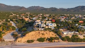 A coastal town with modern buildings, a beach, and mountains in the background. - 3-bedroom  w/ amazing views, waterfront access, resort amenities & hot/cold tub (El Sargento, La Ventana)
