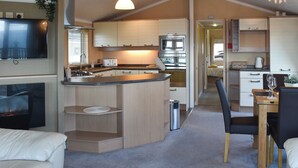 Een compacte keuken met een centraal eiland, ingebouwde apparatuur en een eethoek met een tafel en stoelen.