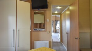 A bedroom with a bed, a wardrobe, a mirror, a television, and a radiator.