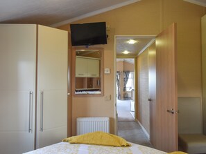 Ein Schlafzimmer mit Bett, Kleiderschrank, Spiegel, Fernseher und Heizkörper.