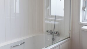 Een moderne badkamer met een douchecabine van glas, een witte badkuip en een wit toilet.
