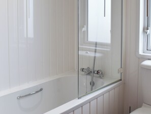 Et moderne badeværelse med en glasafskærmet brusekabine, et hvidt badekar og et hvidt toilet.