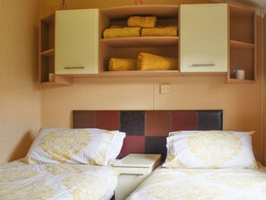 A hotel room with two beds, a nightstand, and a wardrobe with yellow towels. - Sea views don’t come much better than Sunset Lodge. (Llanddulas)