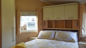 Een slaapkamer met een bed, een kledingkast, een raam met gordijnen en uitzicht op de omgeving.