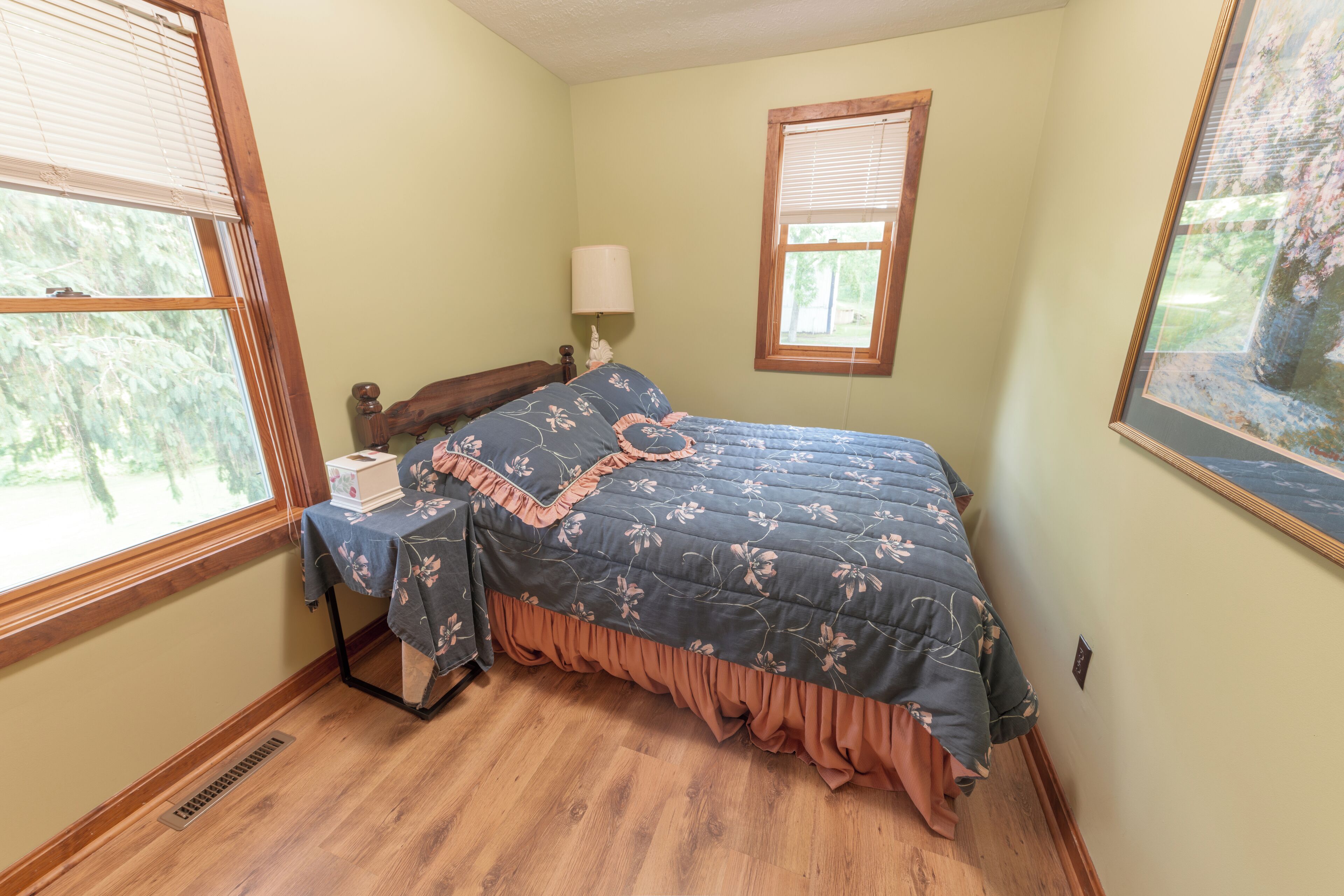 A bedroom with a bed, a nightstand, a lamp, and a window.