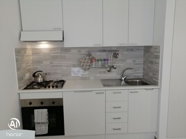 Una cocina moderna con armarios blancos, un lavamanos de acero inoxidable y una estufa a gas.