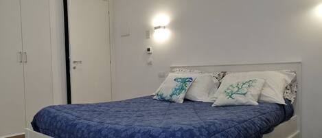 A bedroom with a bed, white wardrobe, and a wall-mounted light fixture.