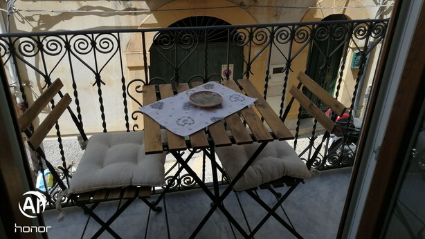 Un balcón con una mesa, sillas y un plato decorativo.