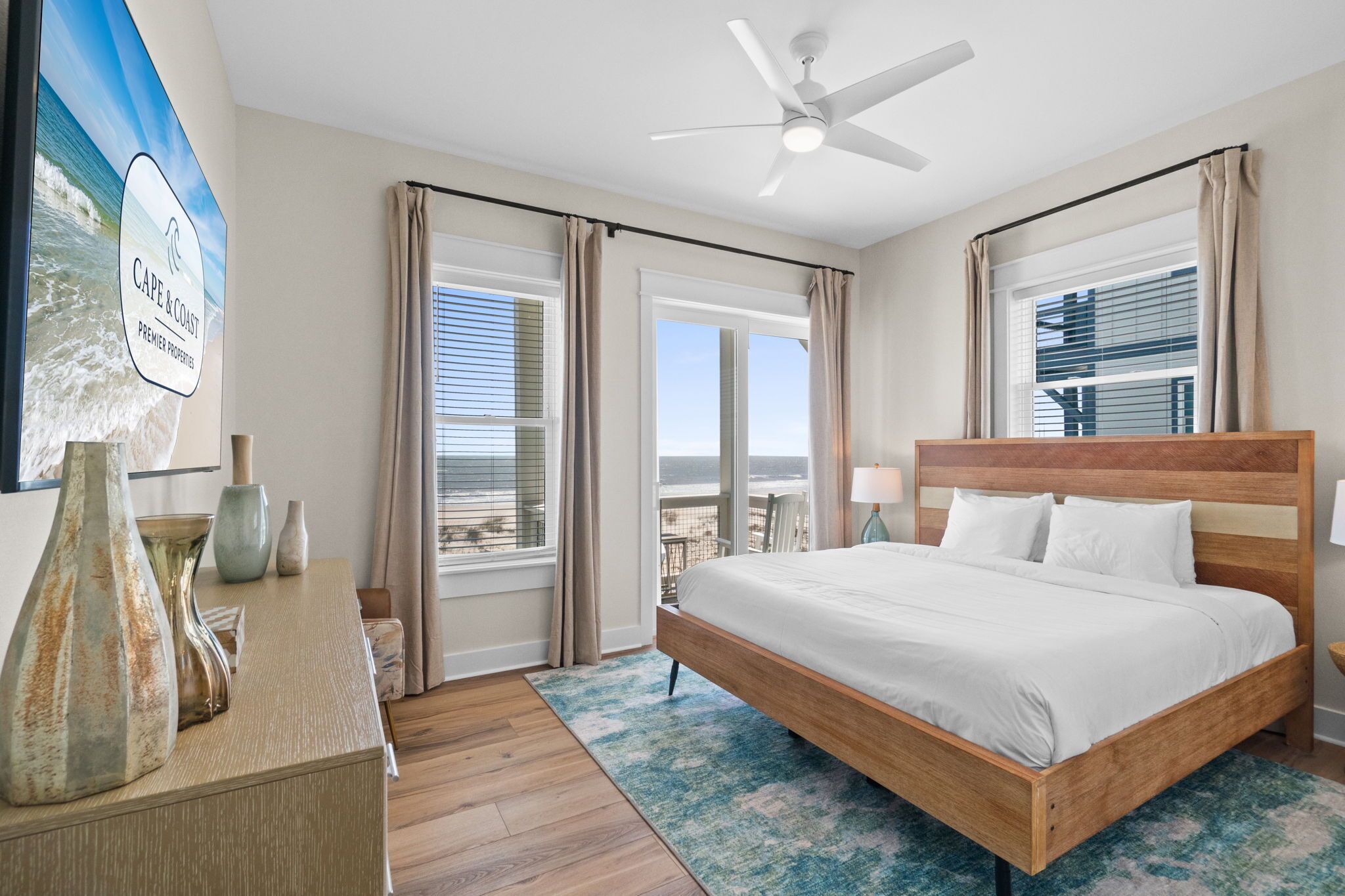 Une chambre avec un lit, un ventilateur de plafond, une vue sur la plage et un panneau accroché au mur.