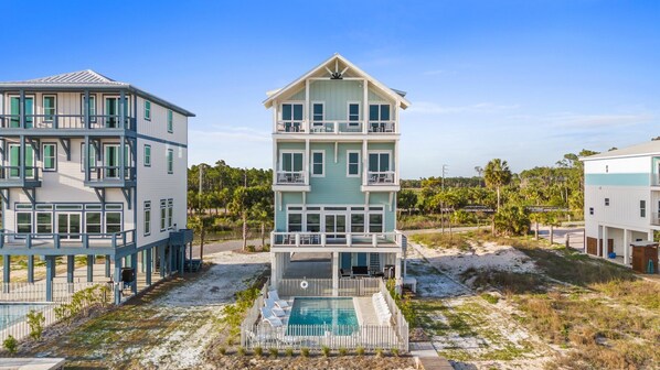 Un inmueble frente a la playa de varios pisos, con piscina, balcones y vista al mar.
