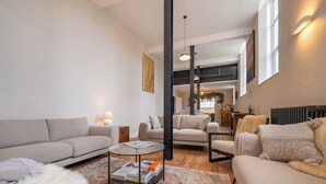 A modern living room with a sofa, armchairs, a coffee table, and a patterned rug. - 5 bedroom accommodation in Seascale (Seascale)