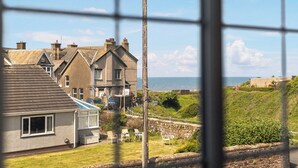 A coastal residential area with houses, a stone wall, and a view of the sea. - 5 bedroom accommodation in Seascale (Seascale)