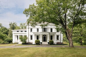 A large, white, two-story building with a symmetrical facade, central entrance, and a well-maintained lawn.