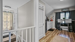 Et moderne køkken med hvide skabe, et sort køleskab og et spiseområde med to barstole og et bord.