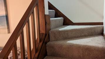 A staircase with wooden railings and carpeted steps.