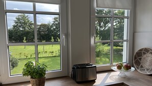 Een keuken met een groot raam, een broodrooster, een geweven mand met een plant en een fruitkar.