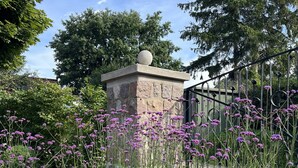 Een tuin met een stenen monument, omgeven door grind en paarse bloemen.