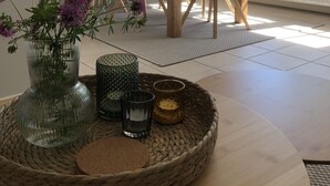 Een eetruimte met een houten tafel, zwarte stoelen en hangende hanglampen.