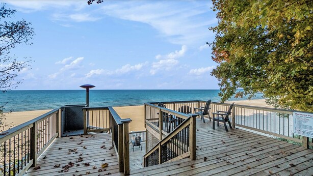 A wooden deck with a railing, a beach view, and a signboard. - Lake Michigan Sunset Views from updated Macatawa home w/private beach access  (Holland)
