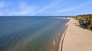 Una playa con aguas cristalinas, un muelle y casas a lo largo de la costa.