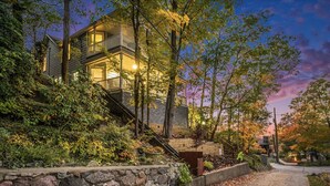 A two-story house with a balcony, surrounded by trees and a stone wall. - Lake Michigan Sunset Views from updated Macatawa home w/private beach access  (Holland)