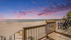 A wooden deck with beach chairs overlooking a sandy beach and ocean, with a sign detailing beach rules and regulations. - Lake Michigan Sunset Views from updated Macatawa home w/private beach access  (Holland)