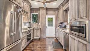 A modern kitchen with stainless steel appliances, wooden cabinetry, and a central island. - Lake Michigan Sunset Views from updated Macatawa home w/private beach access  (Holland)