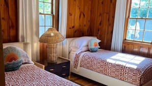 Ein Zimmer mit zwei Betten, Holzwänden und großen Fenstern.