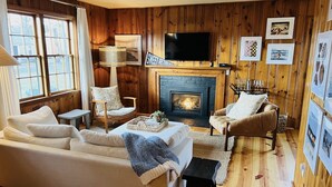 Ein gemütliches Wohnzimmer mit Kamin, Holzwänden und einem Fernseher.