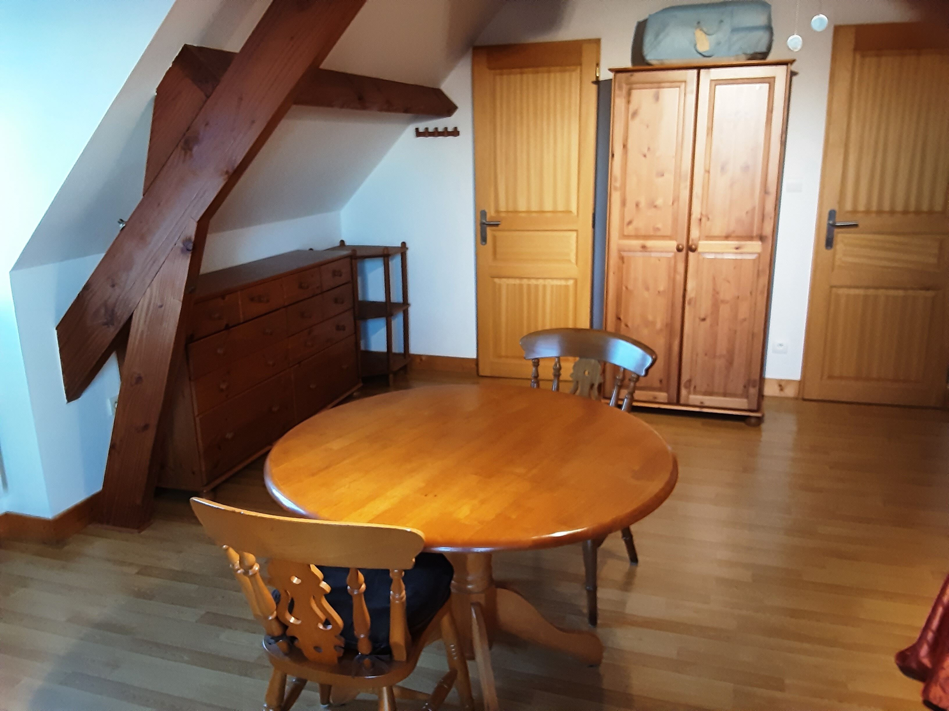 A dining area with a wooden table and chairs, a wooden cabinet, and a door with a handle.