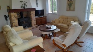 Una sala de estar con chimenea de ladrillo, televisor, sofá y mesa de centro.