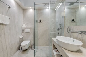 A modern bathroom with a glass-enclosed shower, a white sink, and a toilet.